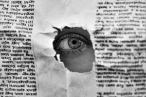 oeil qui se cache derrière un journal